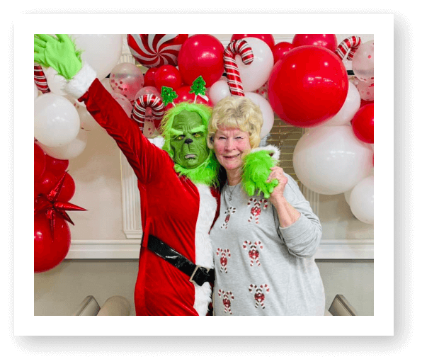 Elderly Woman Posing with Grinch Character During Holiday Event at Assisted Living Facility