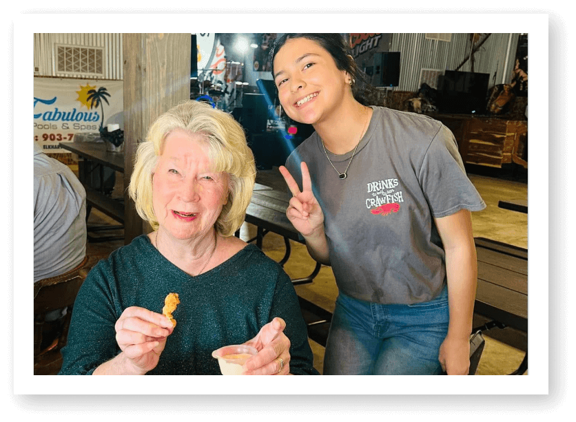 Elderly Woman Enjoying Snack with Young Volunteer at Assisted Living Facility