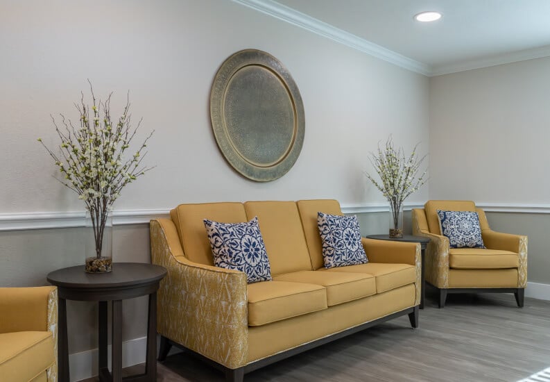 Common Area with Gold Sofa and Decorative Wall Art at Assisted Living Facility
